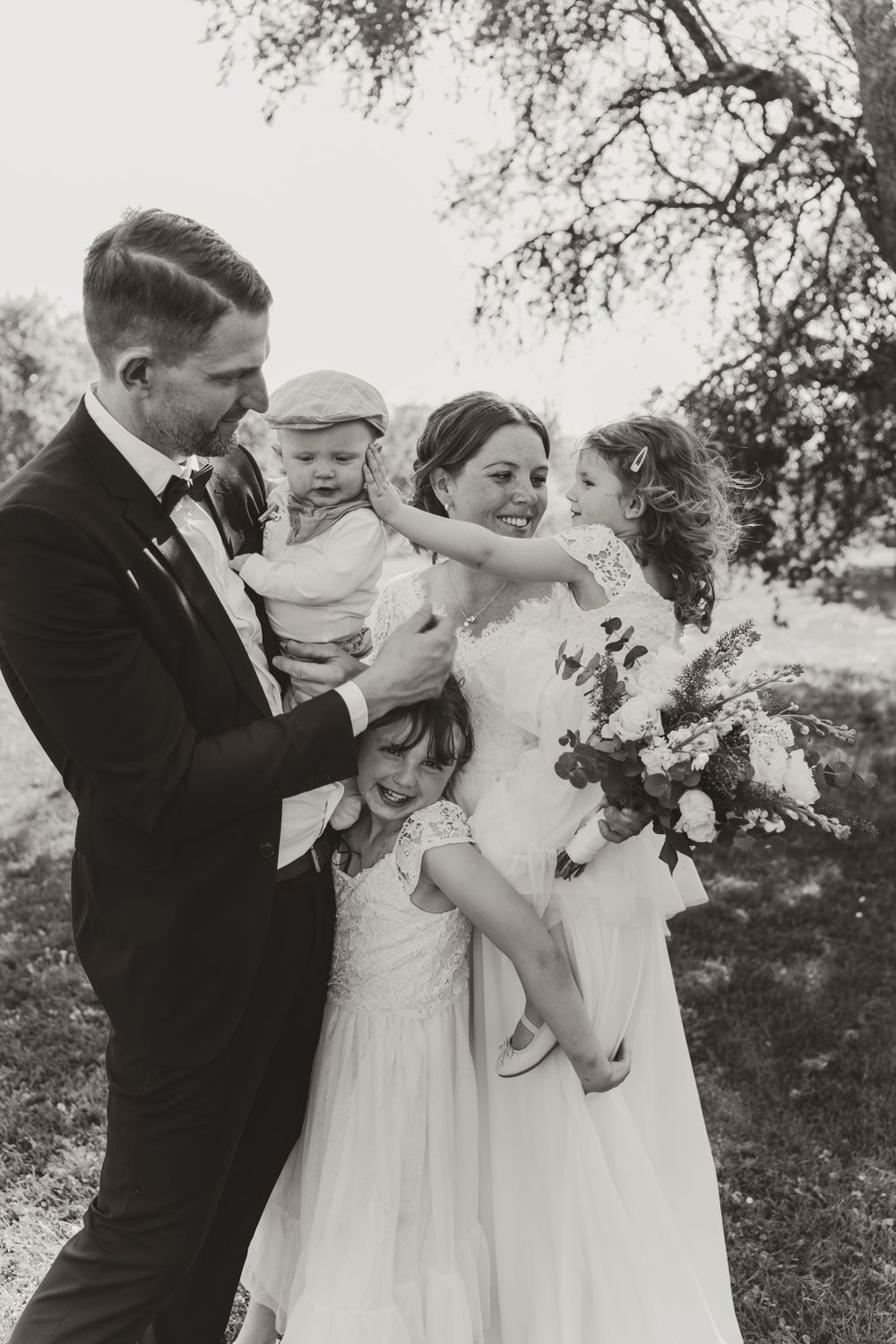 Black and white portrait of wedding couple with children outdoors.