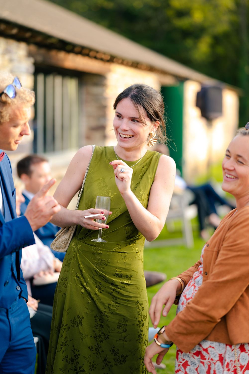 People in colorful attire dance and celebrate at an outdoor party on a sunny day.