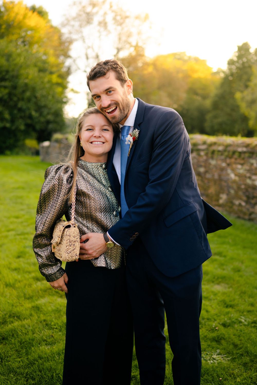 A couple shares a joyful moment together outdoors on a grassy field during golden hour.