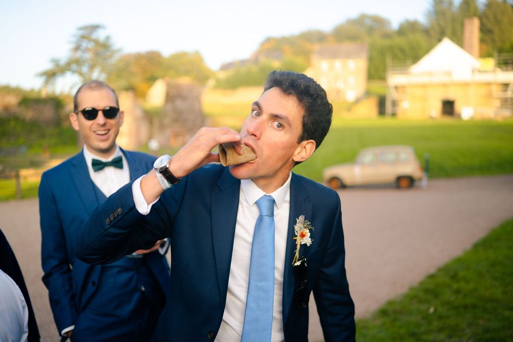 Four candid photos show people in formal navy suits and blue ties at an outdoor event during golden hour.