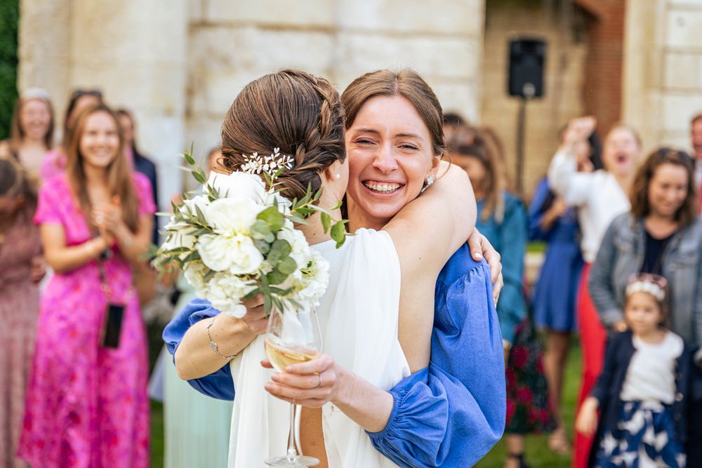 A joyful wedding celebration moment with guests and a bouquet in front of a stone building.
