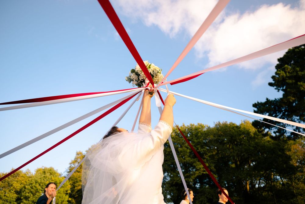 Close-up views of a white maypole with red ribbons against a blue sky with white clouds in multiple angles.