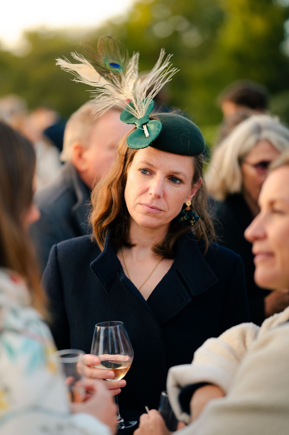 People enjoying cocktails and conversation at an elegant outdoor social gathering with green decor accents.