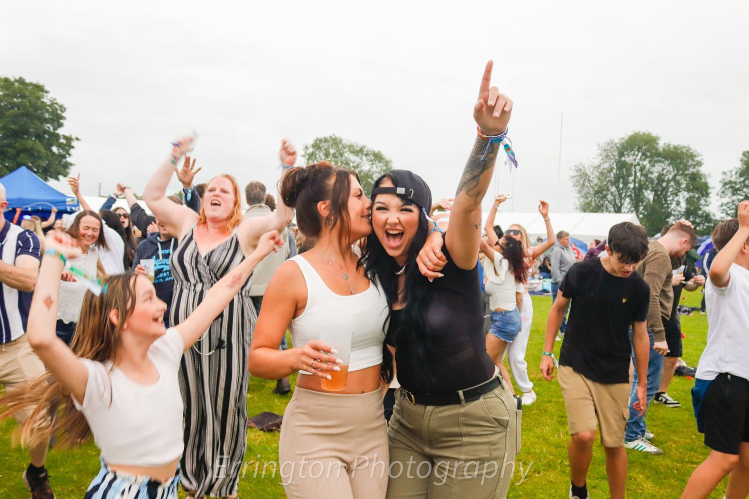 Enthusiastic crowd members dance and cheer at an outdoor festival.