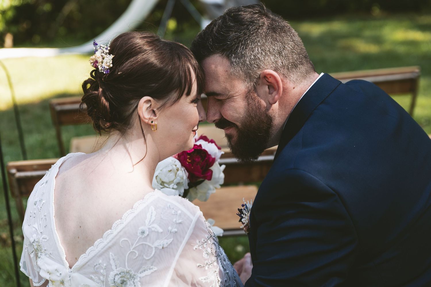 Intimate wedding moment captured with bride holding red bouquet.