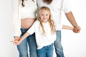 Family wearing white shirts and jeans in minimalist studio setting. Middle TN maternity and newborn photographer.