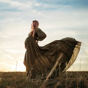 Expectant mom in Flowing green dress captured in motion against sunset sky in open field.  Middle TN Maternity Photographer