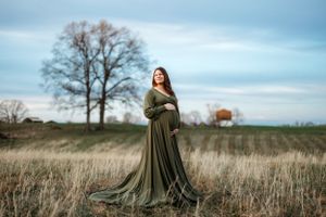 Outdoor maternity photography in an olive dress against a natural field landscape. Middle TN Maternity Photographer