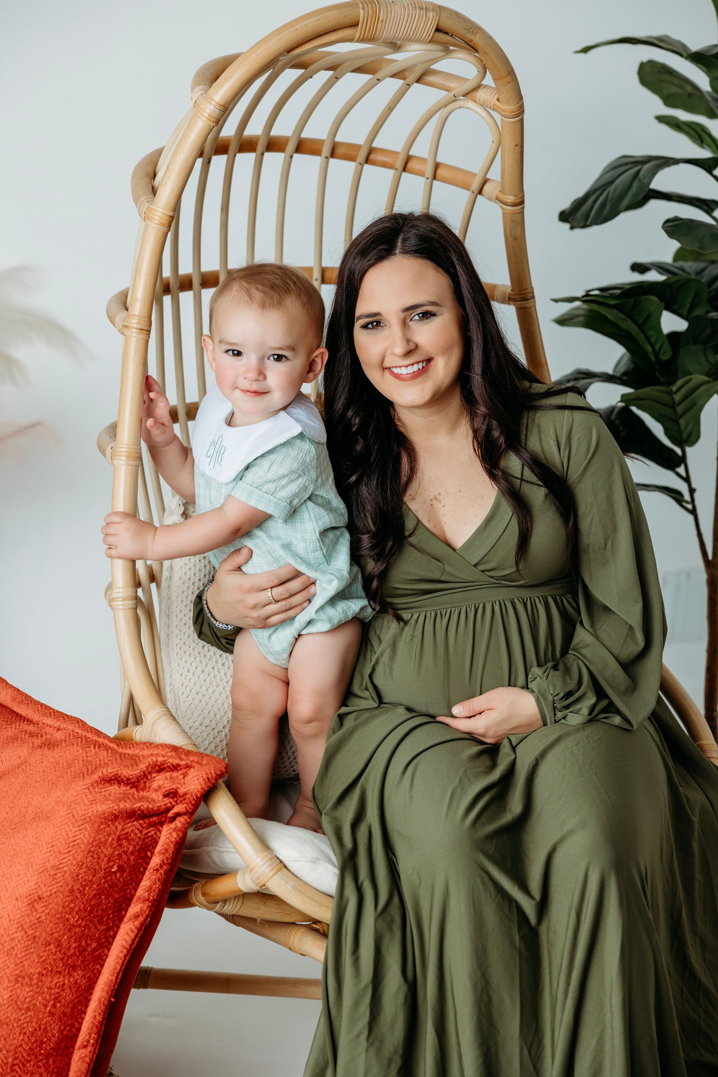 Maternity session with rattan chair featuring olive green dress and bright interior setting. Middle TN Maternity Photographer