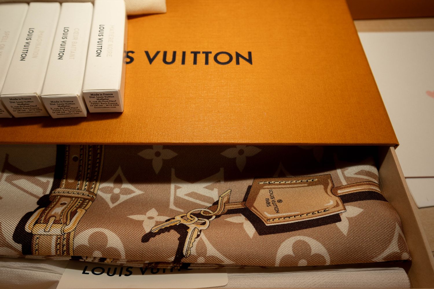 A Louis Vuitton monogram handbag with leather tag displayed in an orange gift box.