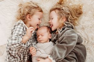 silly sisters lick baby's head newborn session