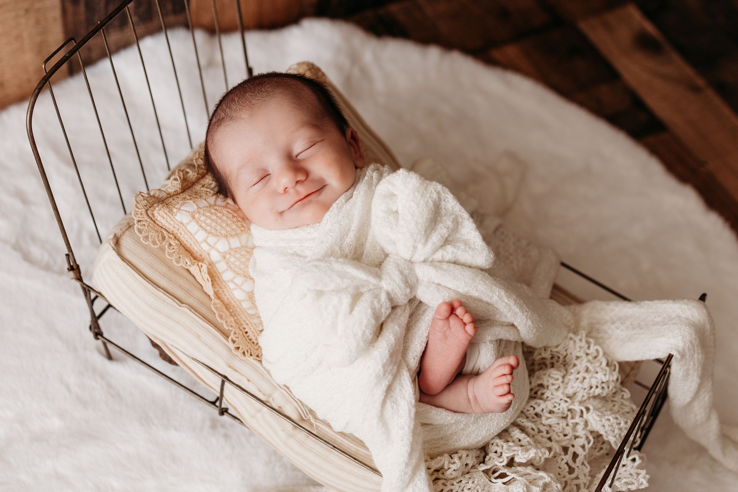 newborn baby smiles in bed prop newborn photography
