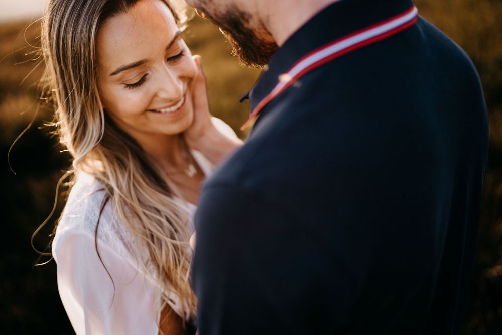 Romantic couple sharing an intimate moment outdoors during golden hour in a natural setting.