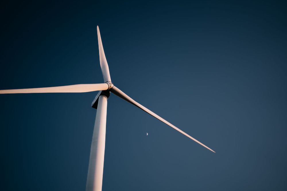 Modern wind turbine blade against deep blue sky.