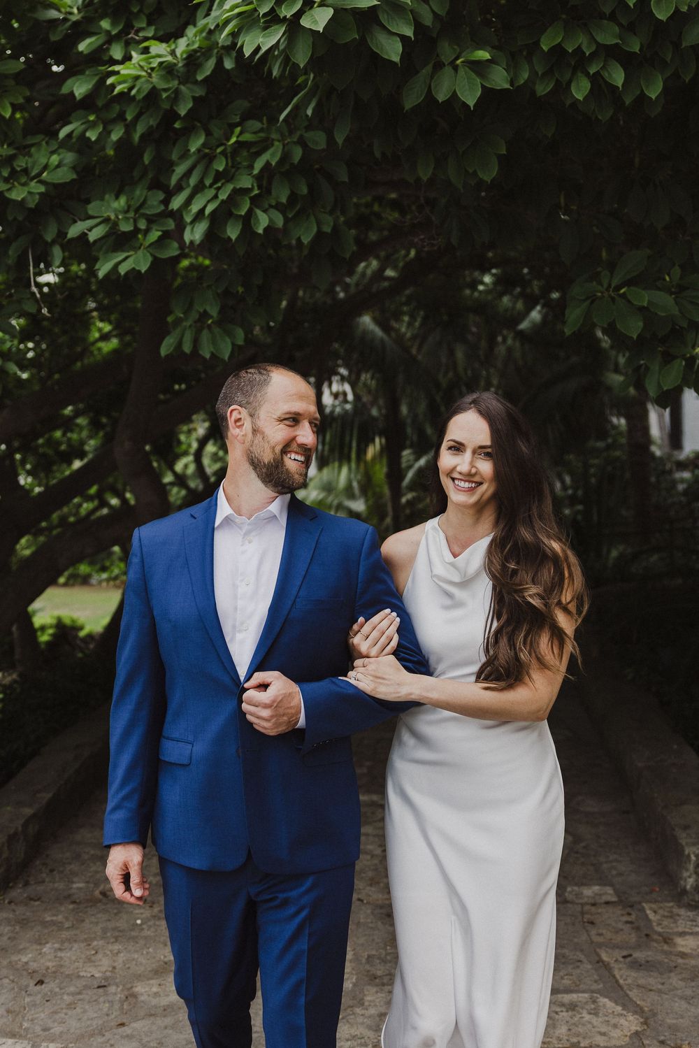 Couple sharing a joyful moment together under lush green foliage.