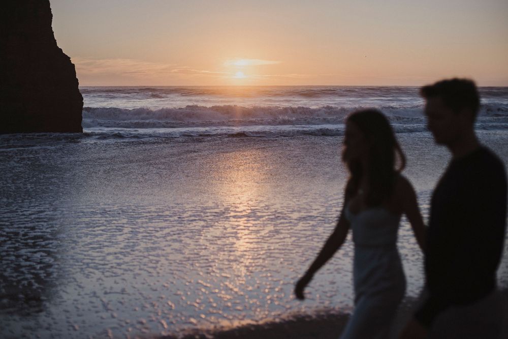 Silhouettes of a couple walking along the beach during a dramatic sunset.