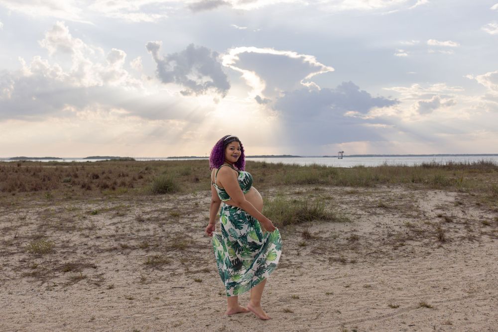 A beachside maternity portrait with flowing green tropical dress.