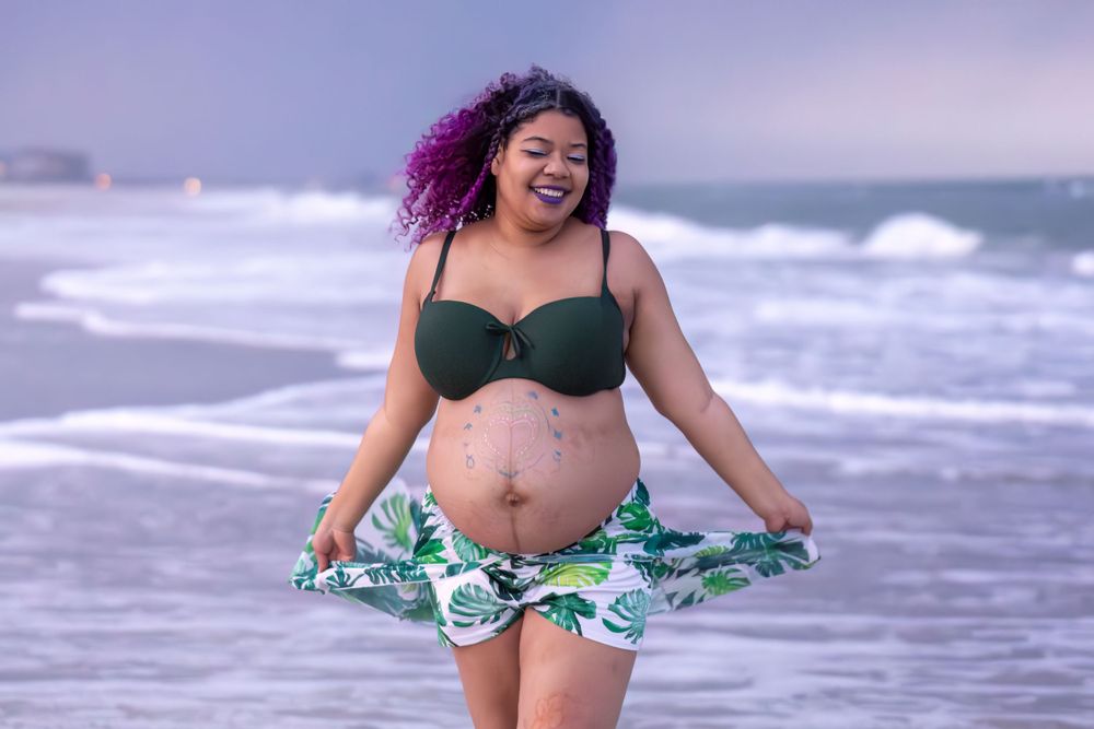 Portrait of a joyful person in a green tropical print swimwear at the beach.