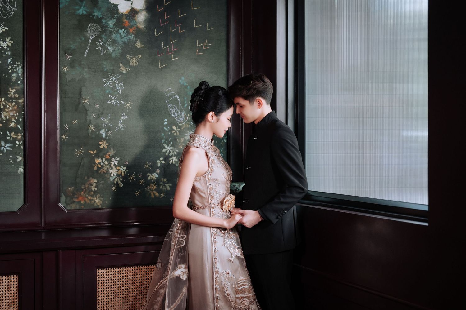 Intimate moment between couple in formal attire against decorative Asian-inspired wall.