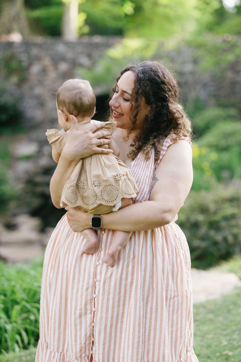 Loving moment captured between parent and baby against a lush garden backdrop.