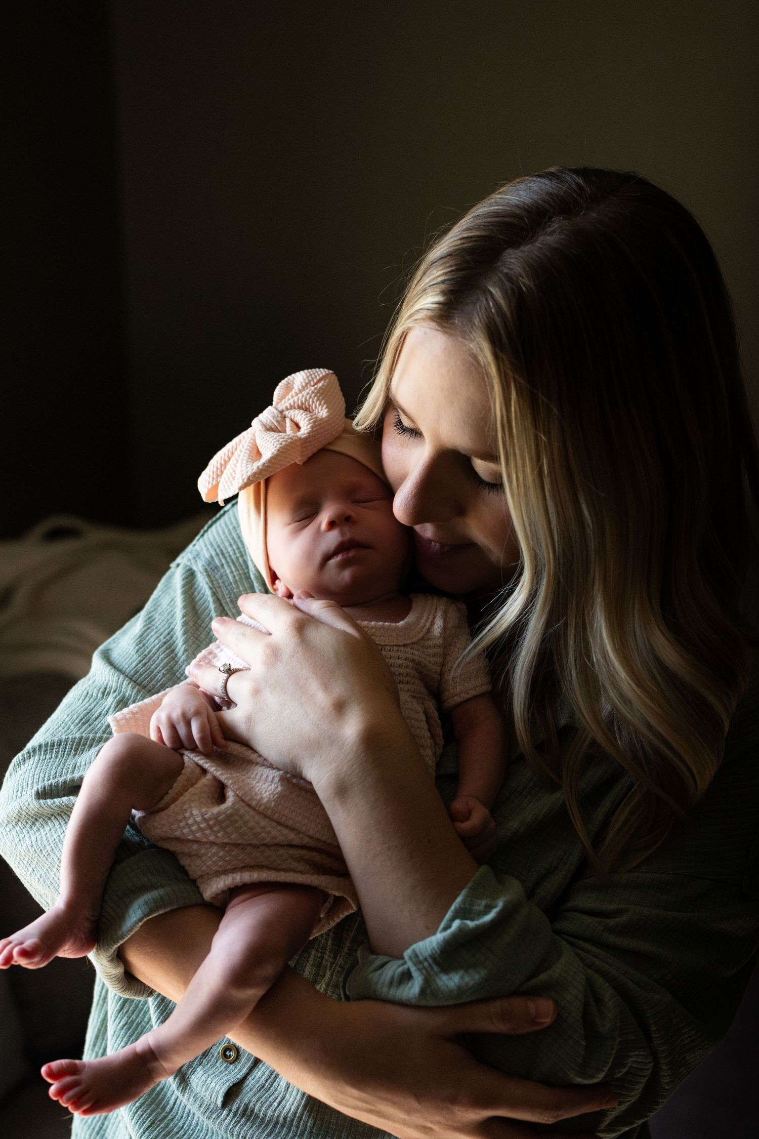 Intimate portrait of a tender moment with a sleeping newborn in natural window light.