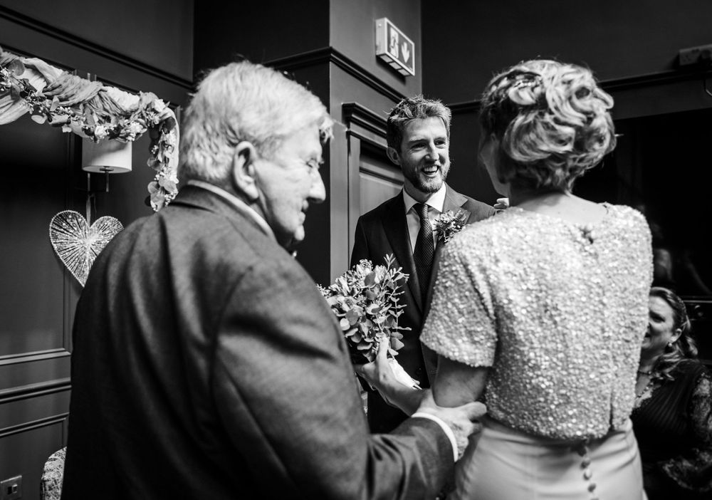 A black and white photograph showing wedding attendees in a decorated indoor venue.