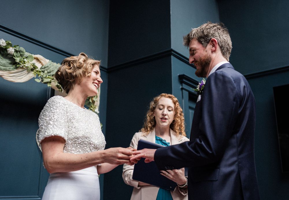 A wedding ceremony taking place in a cozy venue with navy walls and romantic decor.