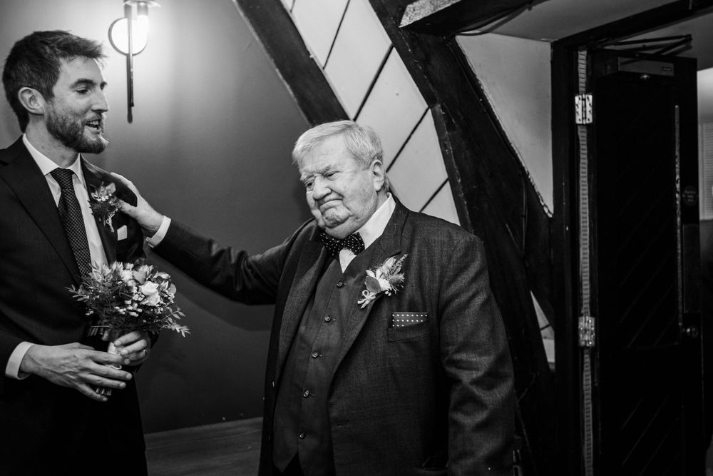 A candid black and white moment showing two generations sharing a joyful interaction at a formal event.
