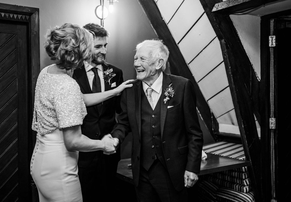 An emotional black and white wedding moment showing three people sharing a tender exchange.