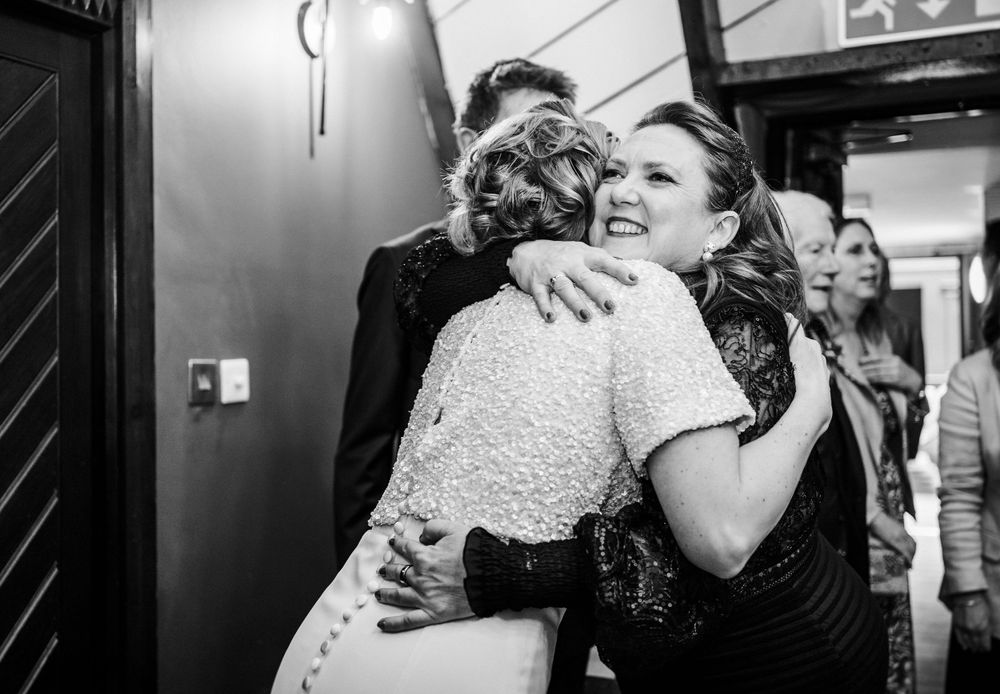 A joyful embrace captured in black and white during a wedding celebration.