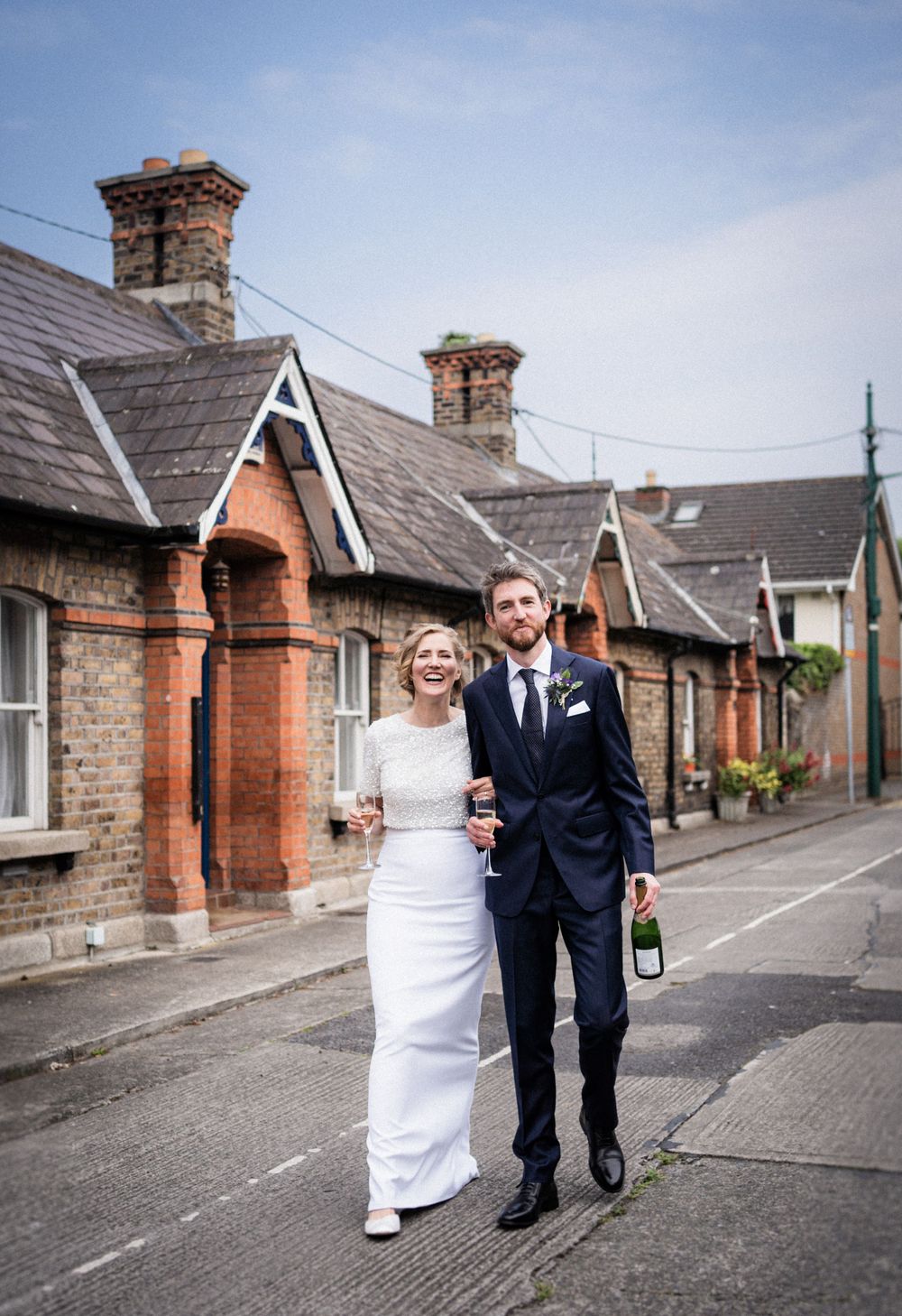 A happy couple strolls down a street lined with vintage brick cottages.