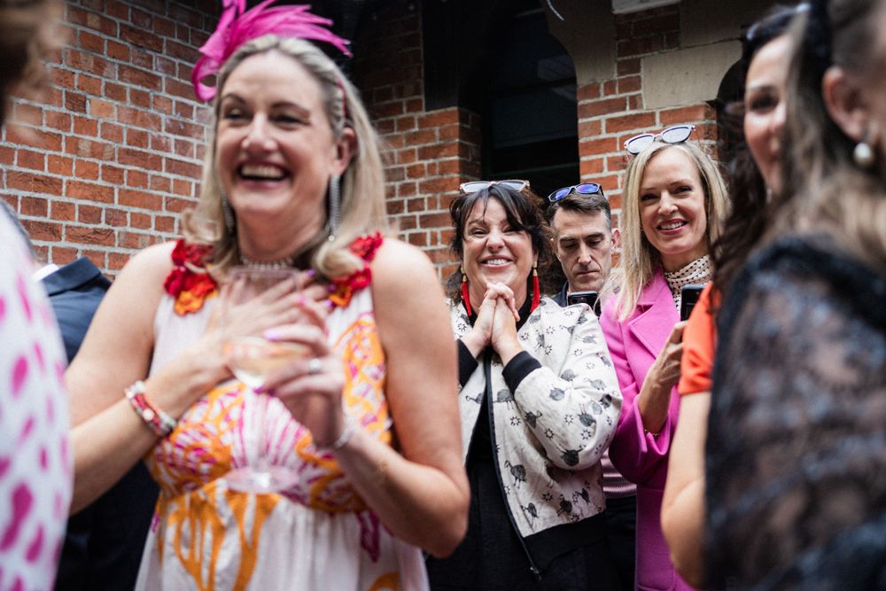 Joyful celebration at a wedding reception with guests in vibrant attire clapping and cheering.