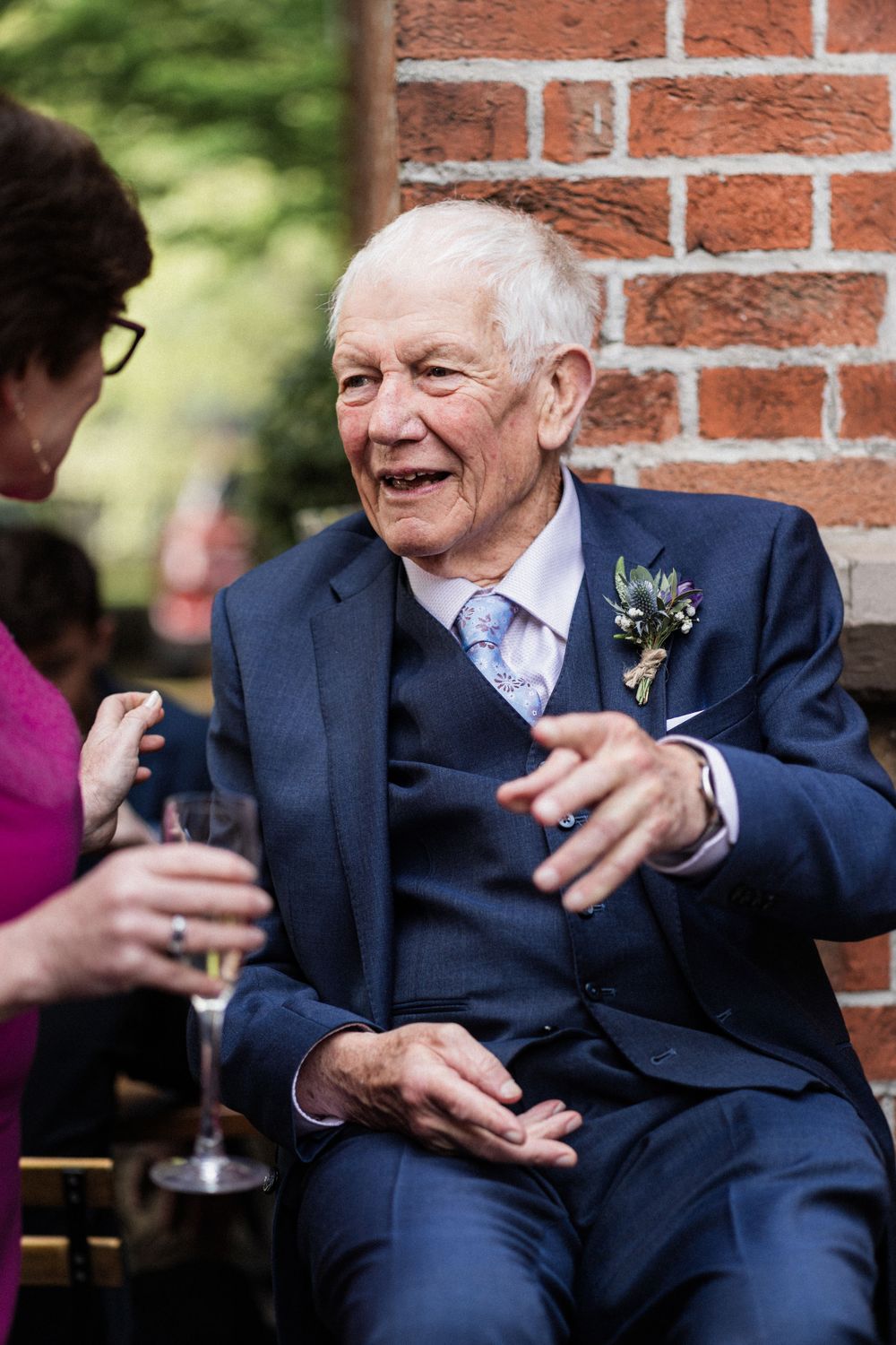 An elegantly dressed senior guest in a navy suit shares a warm moment during the wedding reception.