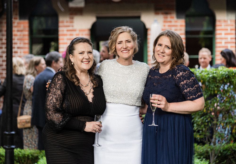 Three guests pose together during the wedding celebration in formal attire.