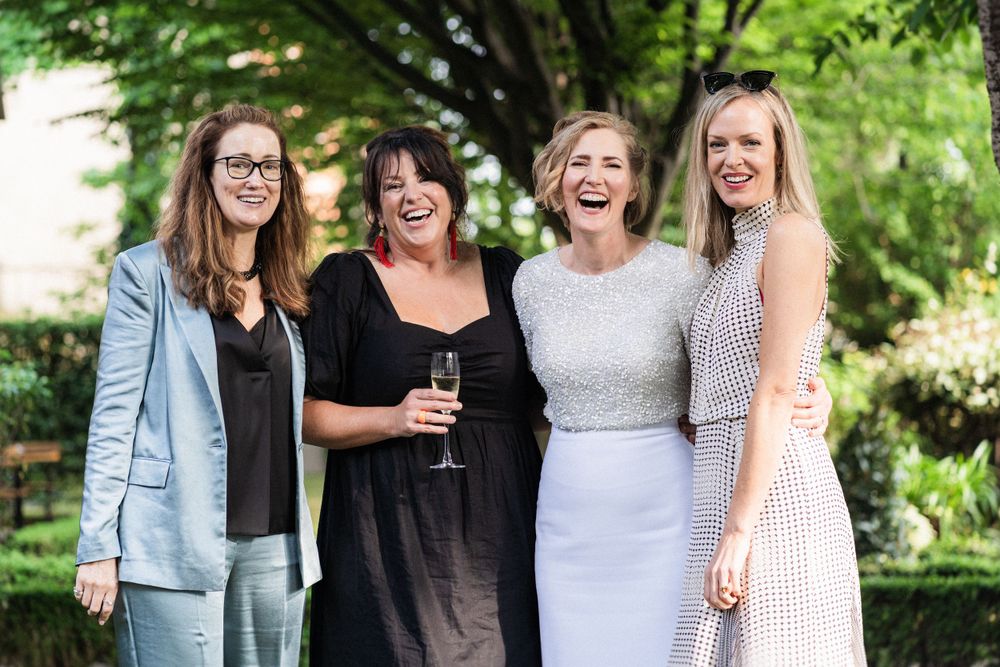 Four people share laughter together at an outdoor gathering.
