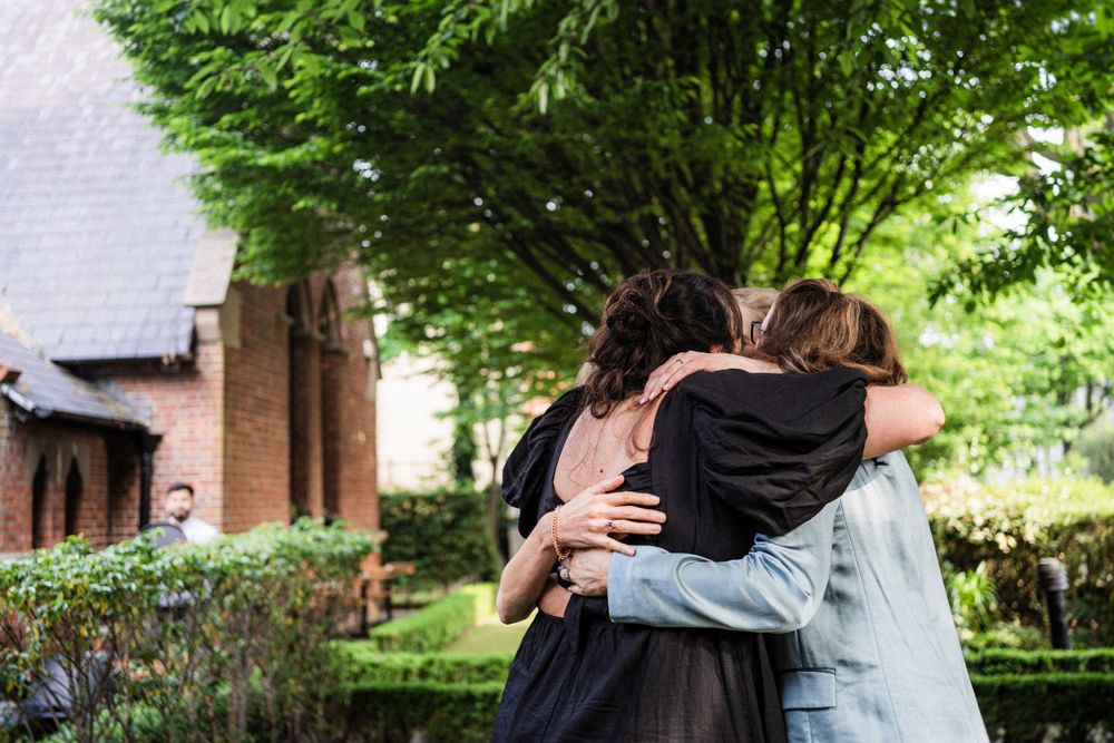 Two people share an emotional embrace in a garden setting.