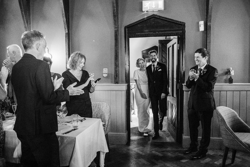 A black and white photo of guests mingling at a formal indoor event.