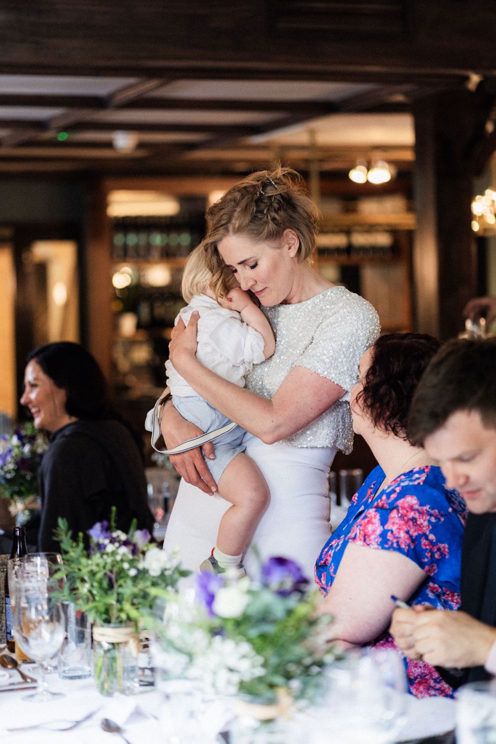 A tender moment between parent and child during a wedding reception with floral table decor.
