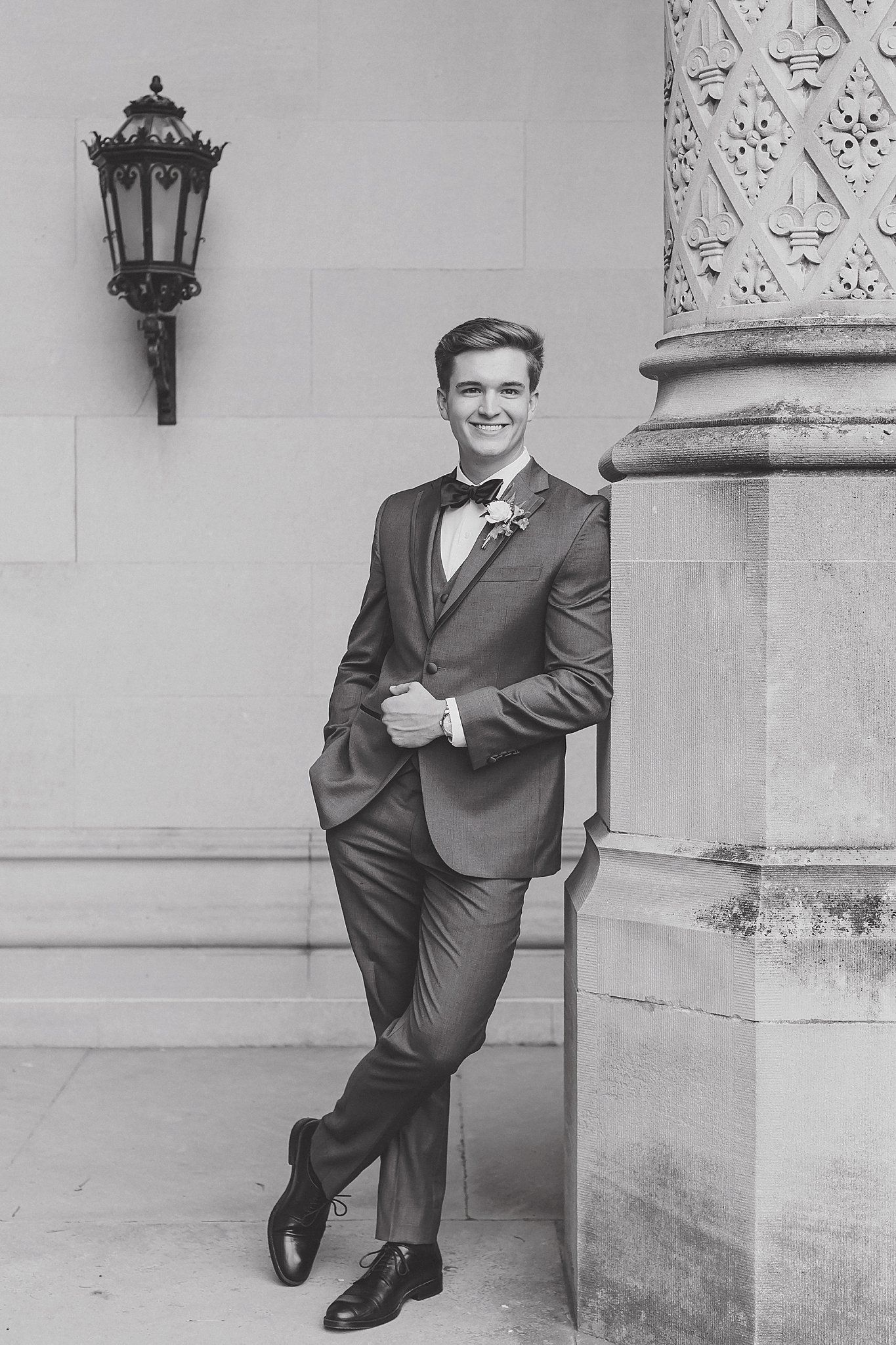 A formal portrait session in a classic stone corridor with elegant architectural details and vintage lanterns.