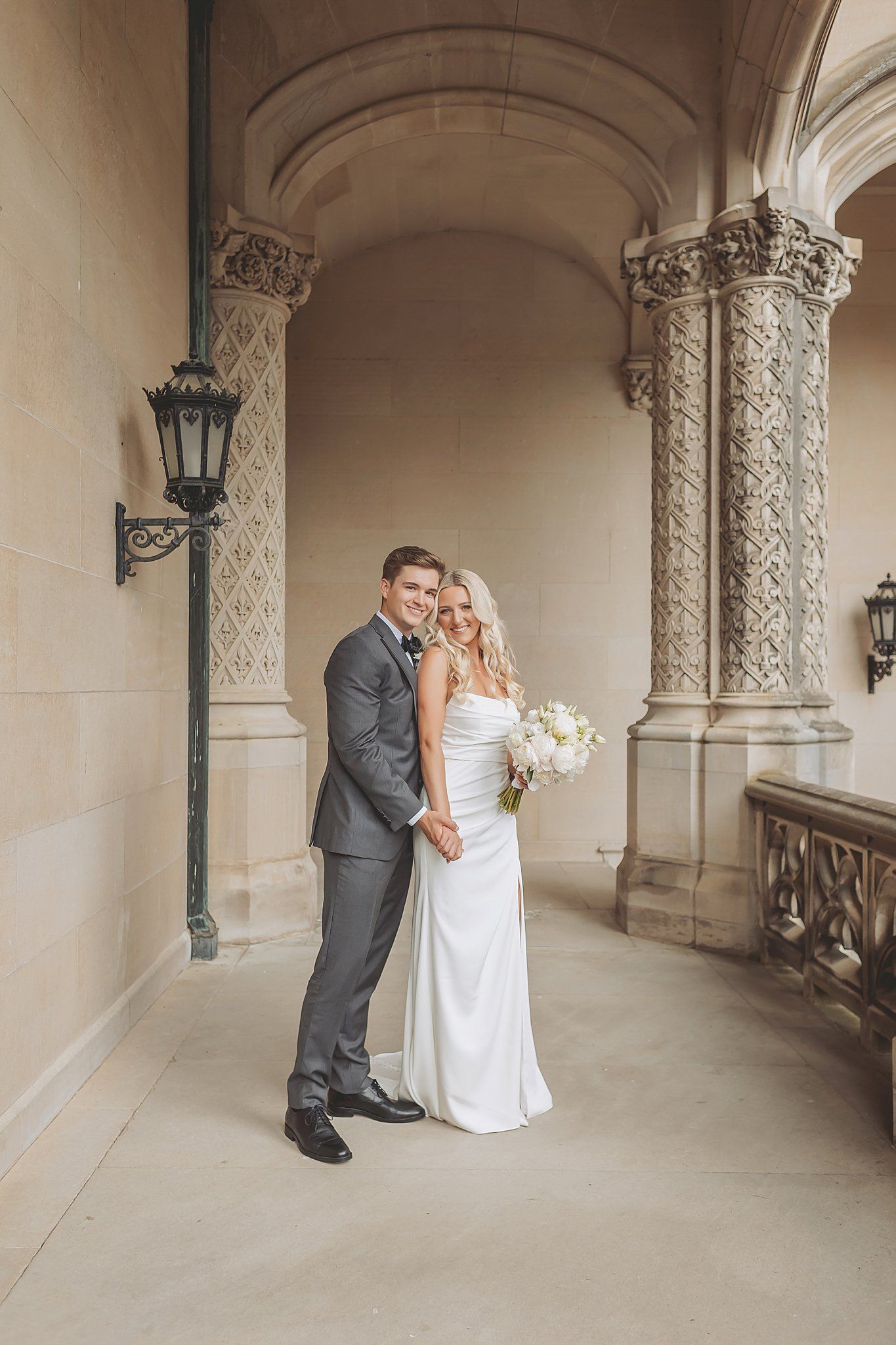 A romantic wedding photo shoot in an ornate stone archway with classic architectural elements.
