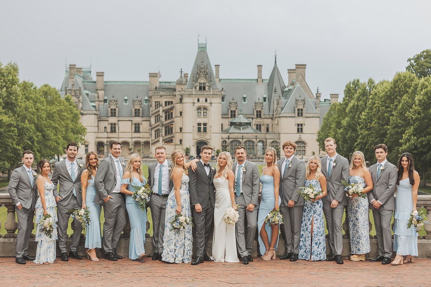 Large wedding party in coordinated blue and grey attire lined up at Biltmore Estate.