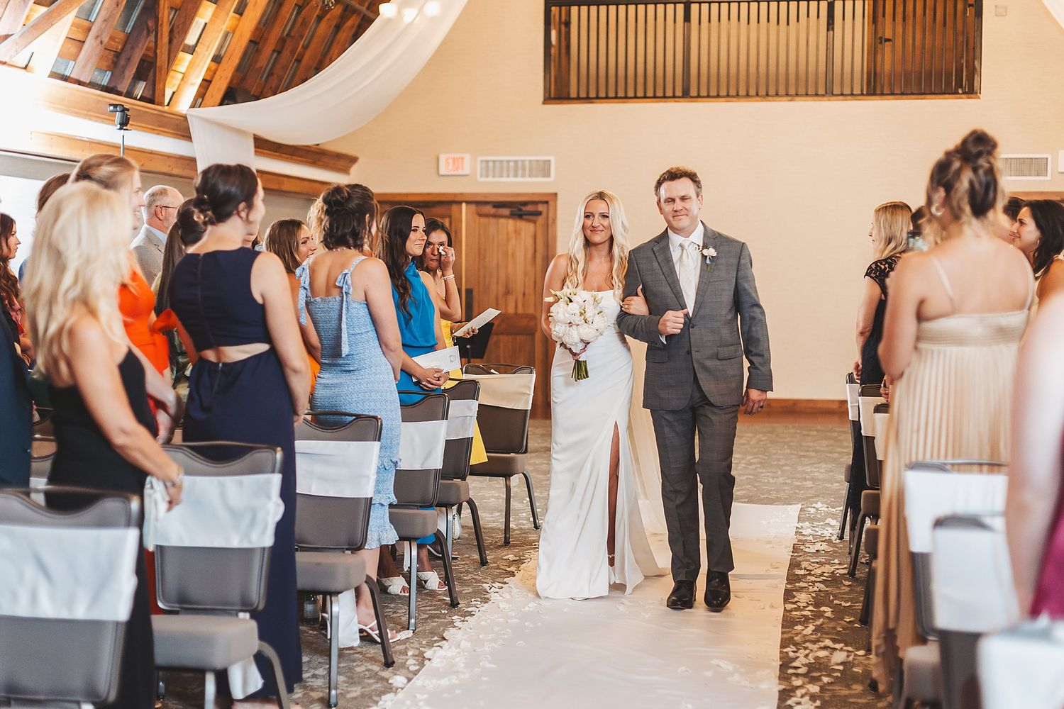 Wedding ceremony recessional in rustic chapel with wood beam ceiling.
