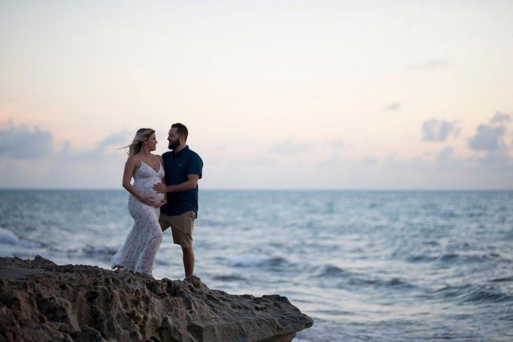 Couple embracing on rocky oceanfront during golden hour.