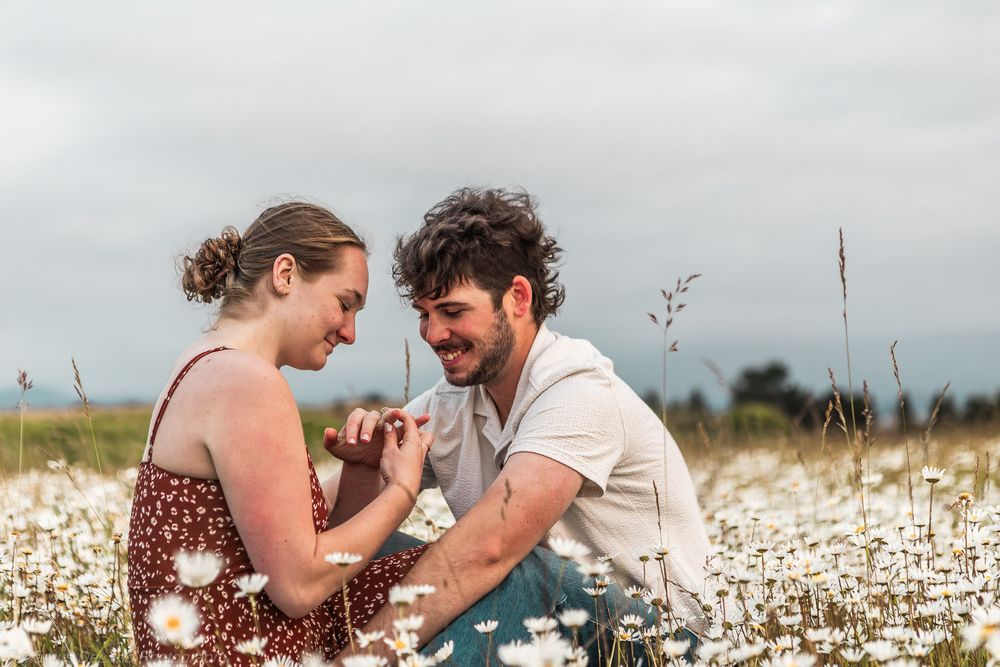 A couple sits intimately in a blooming cotton field during a romantic outdoor photoshoot.