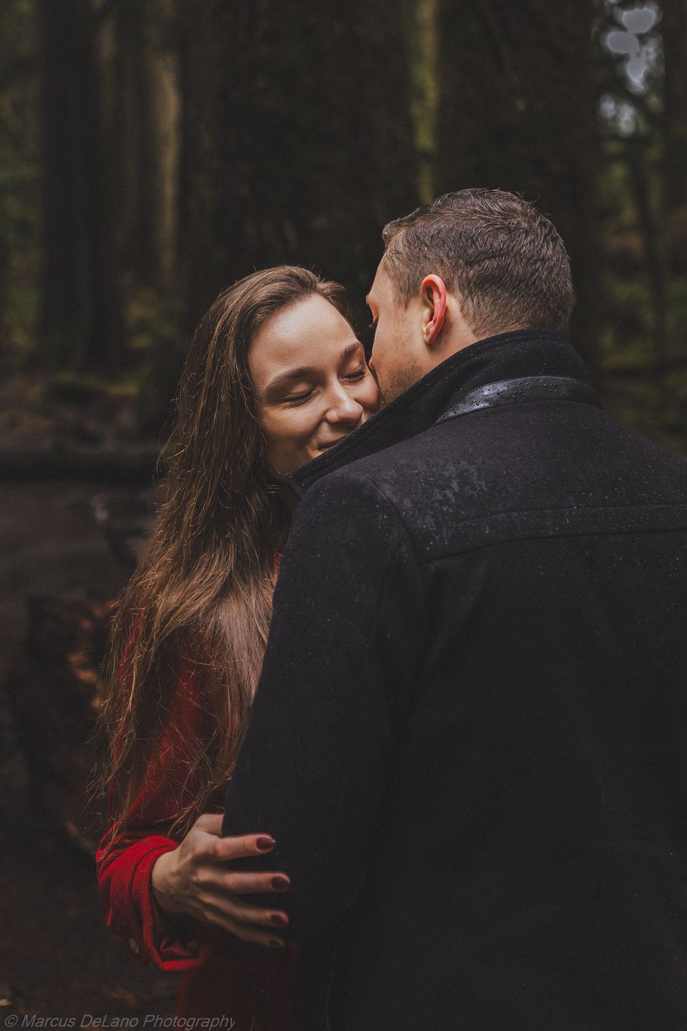 A romantic couple shares intimate moments in a moody forest setting with dramatic lighting and red accents.