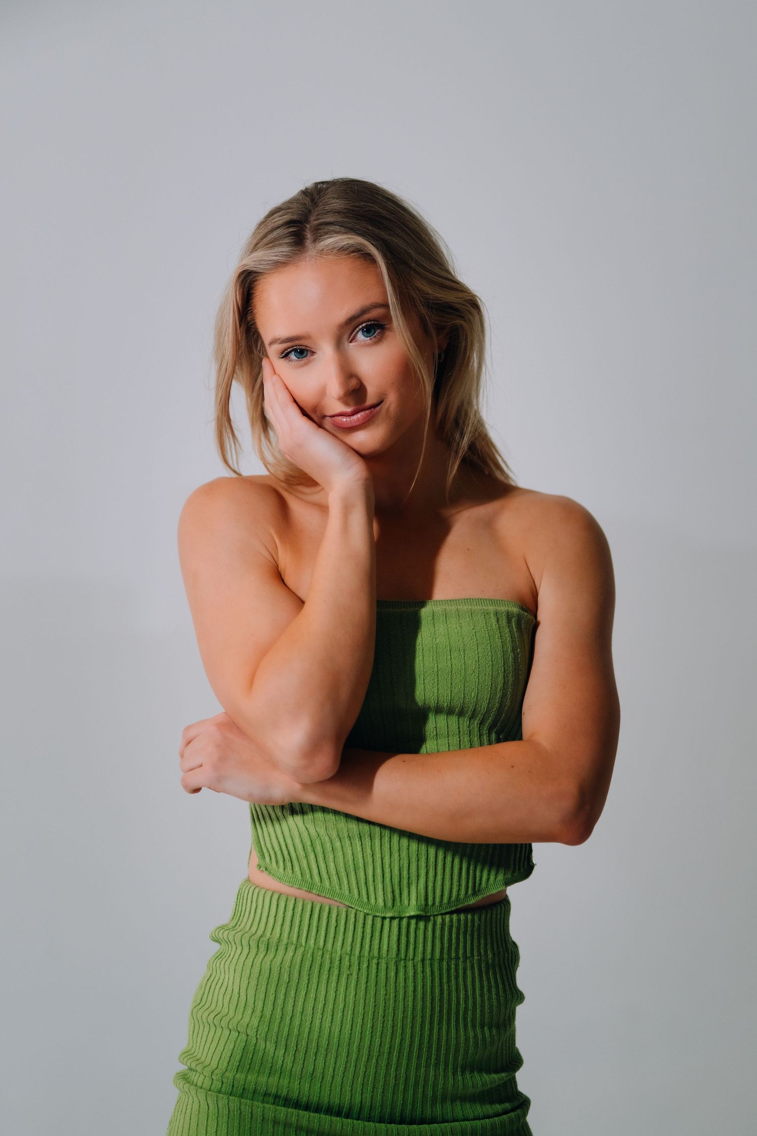 Fashion portrait series showing a woman in a green ribbed tank top against a gray background.