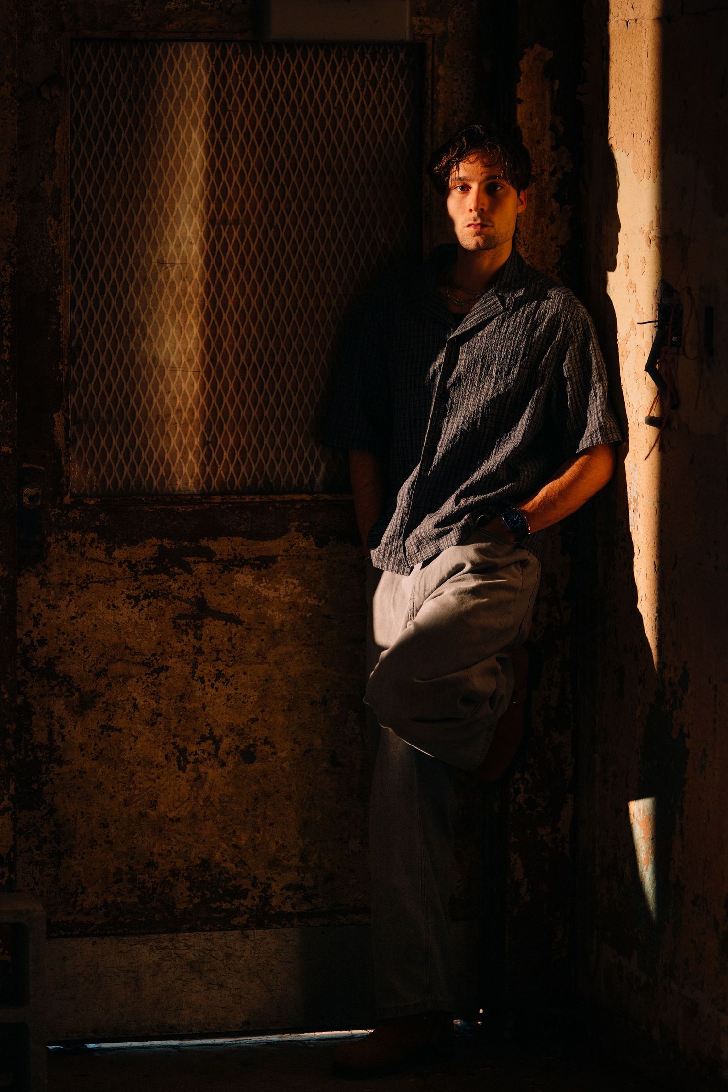 Moody portraits in industrial setting with dramatic shadow and lighting effects.
