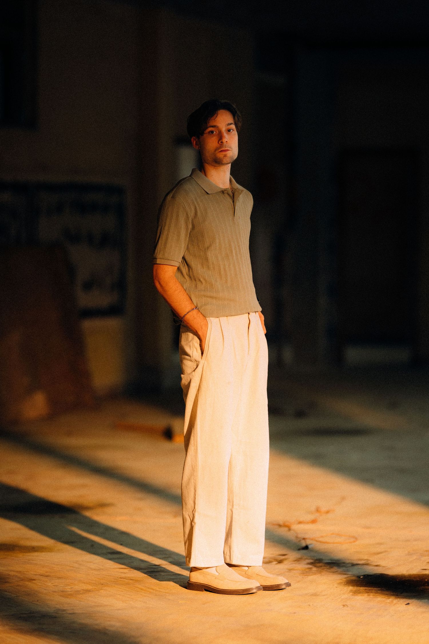 Figure walks through dramatic shadows in minimalist white outfit.