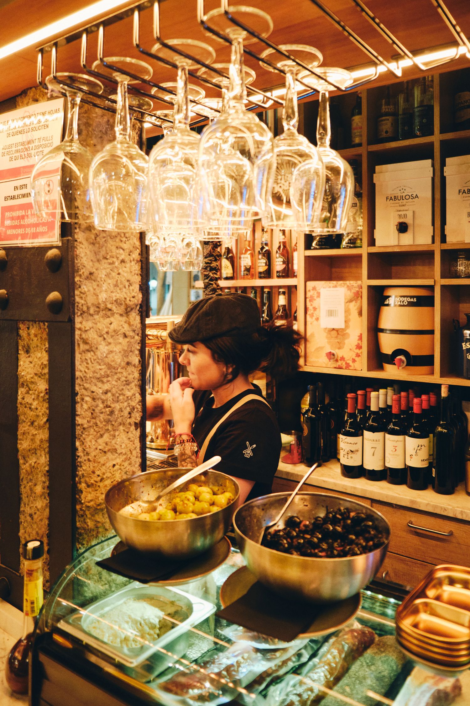 Traditional Spanish tapas bar with hanging wine glasses and olives in serving bowls.
