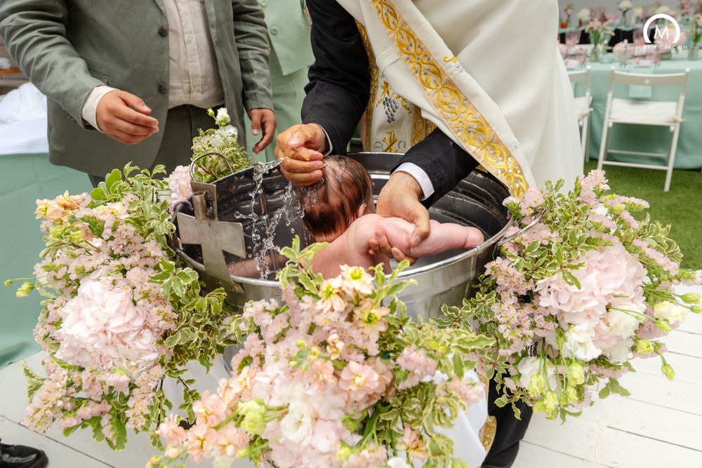 Beautiful floral arrangements with pink blooms and lush greenery surround a display on an outdoor table.